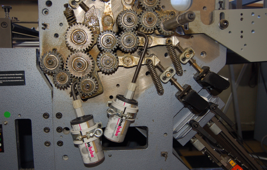 Zwei simalube Schmierstoffgeber 125ml schmieren die Zahnräder einer Ausrüstungsmaschine in einer Druckerei automatisch und konstant bis zu einem Jahr.
