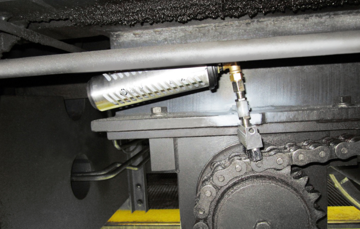 La cadena de transmisión de una grúa giratoria sobre raíles se instala con un lubricador simalube de 250 ml, senos incluidos, para lubricarla y limpiarla automáticamente.