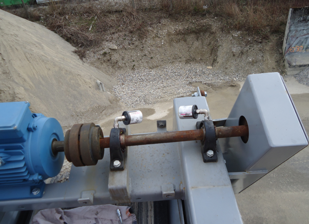 Zwei Stehlager an einer Antriebswelle in einem Zementwerk sind mit zwei simalube Schmierstoffspendern automatisch und kontinuierlich geschmiert. 